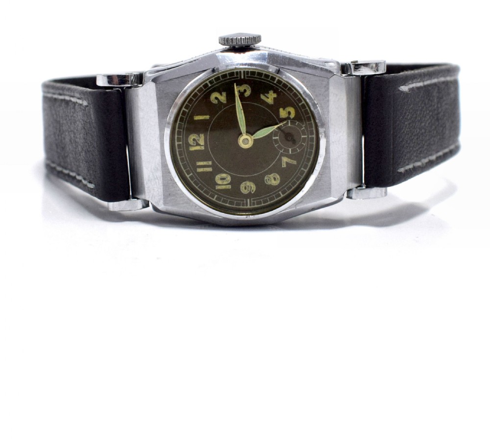 An Art Deco gents manual wristwatch featuring a metallic geometric case, a dark dial with Arabic numerals, and a dark brown leather strap with contrast stitching. View III