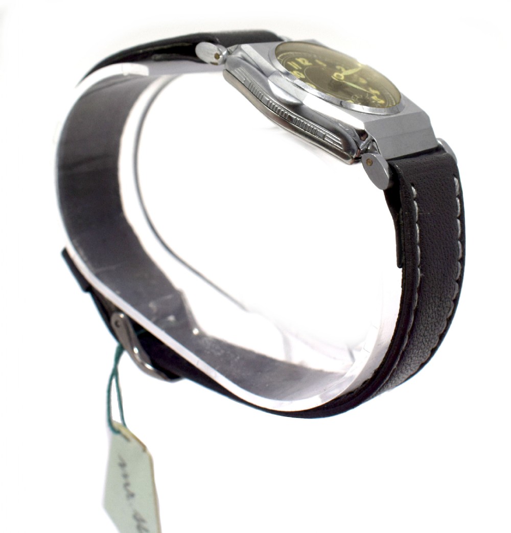 An Art Deco gents manual wristwatch featuring a metallic geometric case, a dark dial with Arabic numerals, and a dark brown leather strap with contrast stitching. View IV