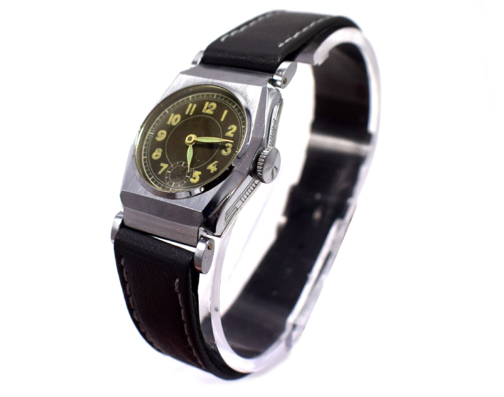 An Art Deco gents manual wristwatch featuring a metallic geometric case, a dark dial with Arabic numerals, and a dark brown leather strap with contrast stitching. View V