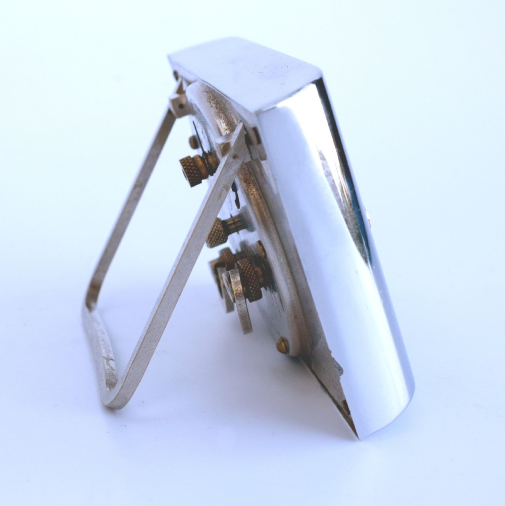 A curved rectangular chrome Art Deco travel clock featuring raised gold-coloured Arabic numerals and matching gold hands. View V
