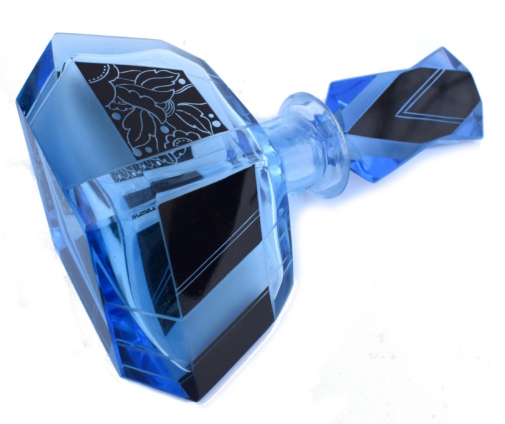 A blue Art Deco glass perfume bottle featuring geometric cut facets, black enamelled panels with etched floral designs, and a tall angular stopper. View II