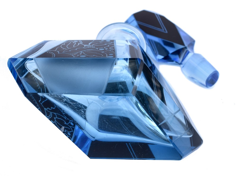 A blue Art Deco glass perfume bottle featuring geometric cut facets, black enamelled panels with etched floral designs, and a tall angular stopper. View IV