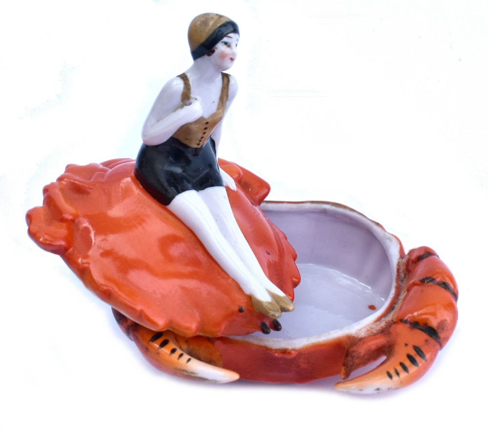 An Art Deco porcelain novelty powder bowl shaped as an orange crab with a bathing belle figure seated on its shell. View II