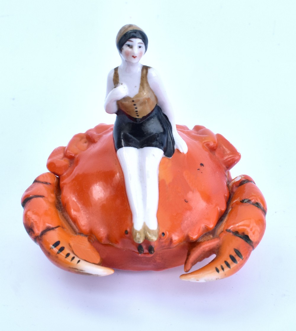 An Art Deco porcelain novelty powder bowl shaped as an orange crab with a bathing belle figure seated on its shell. View VII