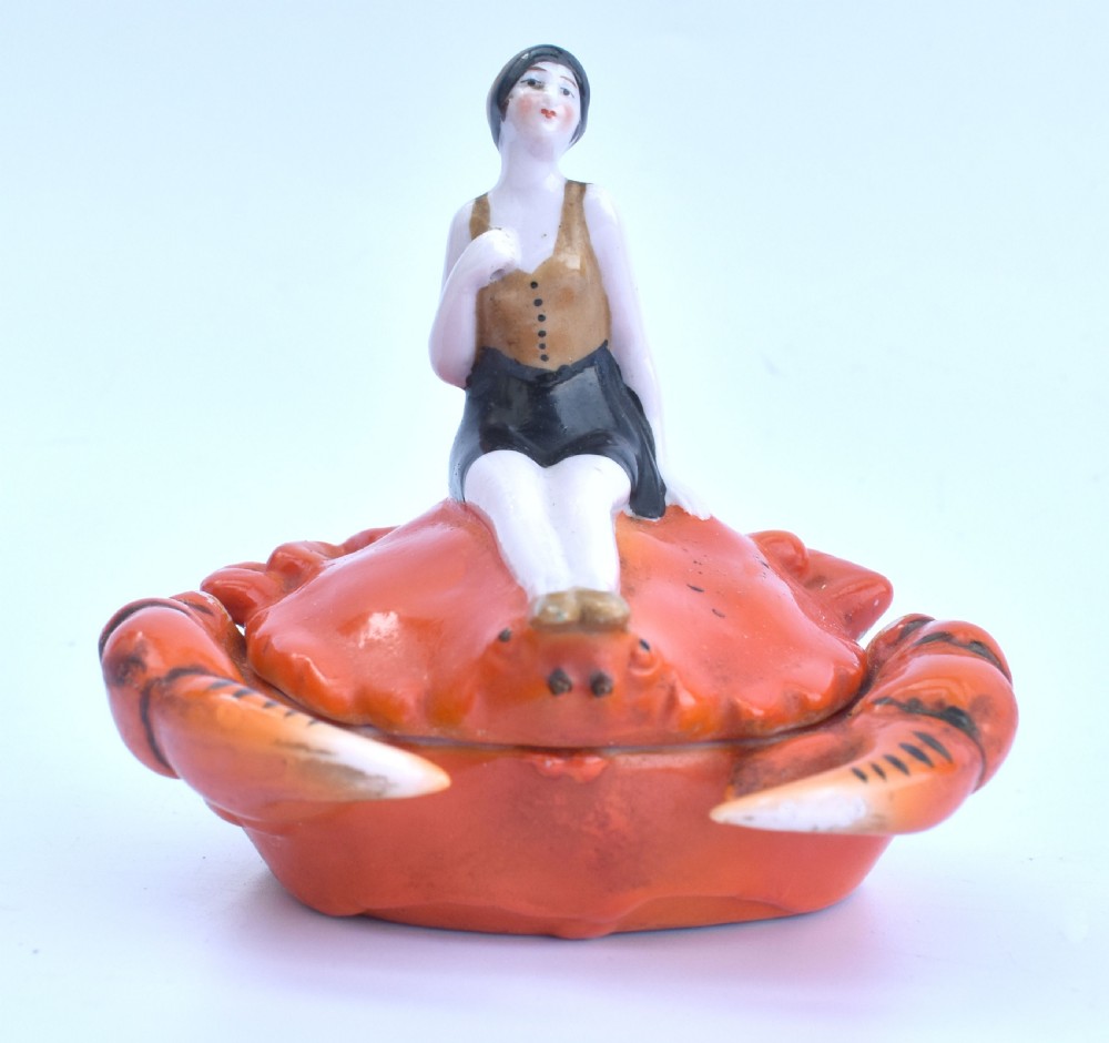 An Art Deco porcelain novelty powder bowl shaped as an orange crab with a bathing belle figure seated on its shell. View VIII
