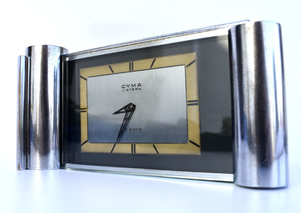 An Art Deco chrome desk clock featuring a rectangular face with geometric hour markers flanked by cylindrical chrome side pillars.