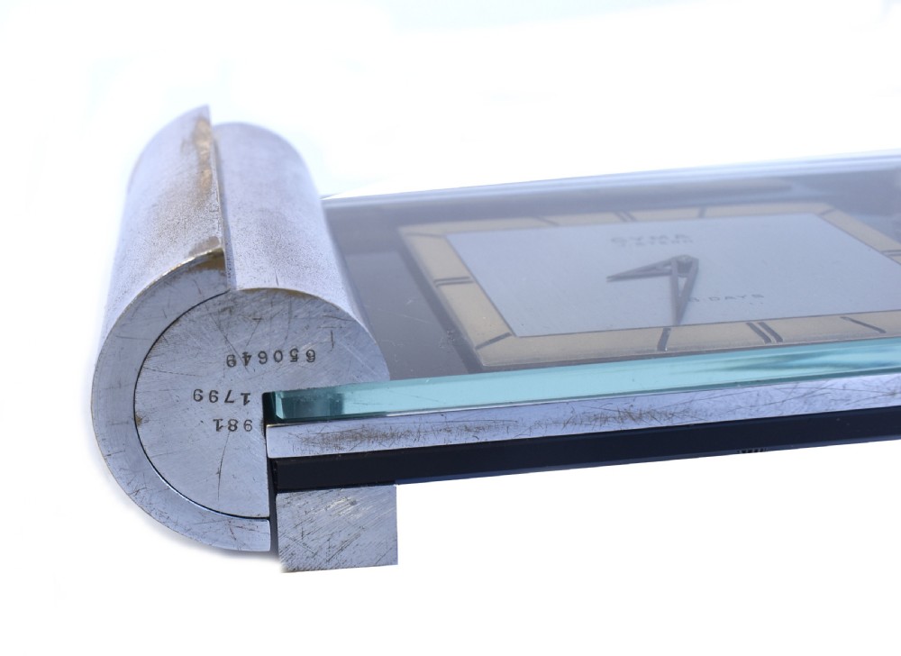 An Art Deco chrome desk clock featuring a rectangular face with geometric hour markers flanked by cylindrical chrome side pillars. View II
