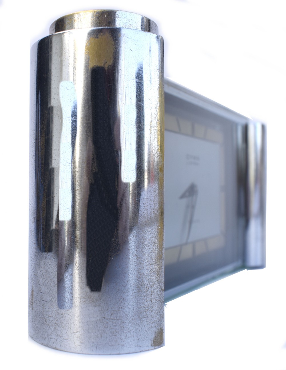 An Art Deco chrome desk clock featuring a rectangular face with geometric hour markers flanked by cylindrical chrome side pillars. View III