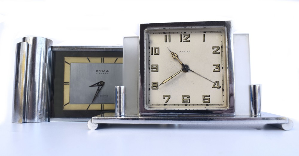 An Art Deco chrome desk clock featuring a rectangular face with geometric hour markers flanked by cylindrical chrome side pillars. View V