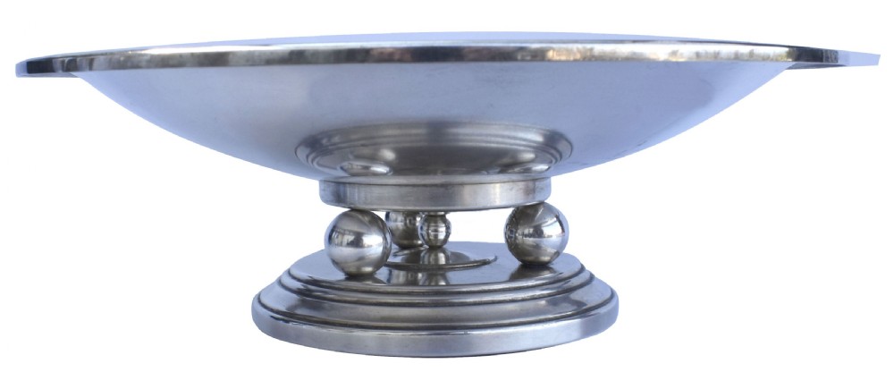 A shallow Art Deco chrome bowl supported by three spherical metal ball feet set on a stepped circular pedestal base.