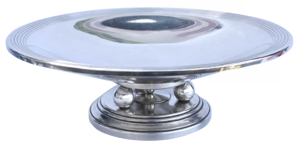 A shallow Art Deco chrome bowl supported by three spherical metal ball feet set on a stepped circular pedestal base. View II