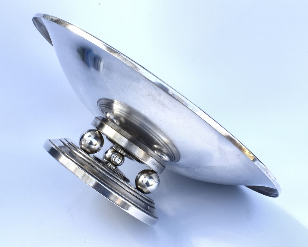A shallow Art Deco chrome bowl supported by three spherical metal ball feet set on a stepped circular pedestal base. View III
