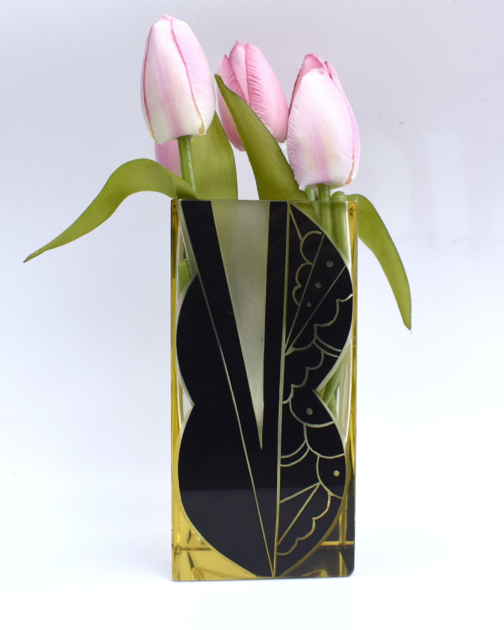 A rectangular Art Deco clear glass vase with a yellow hue, decorated with a stylised geometric black and etched enamel design.