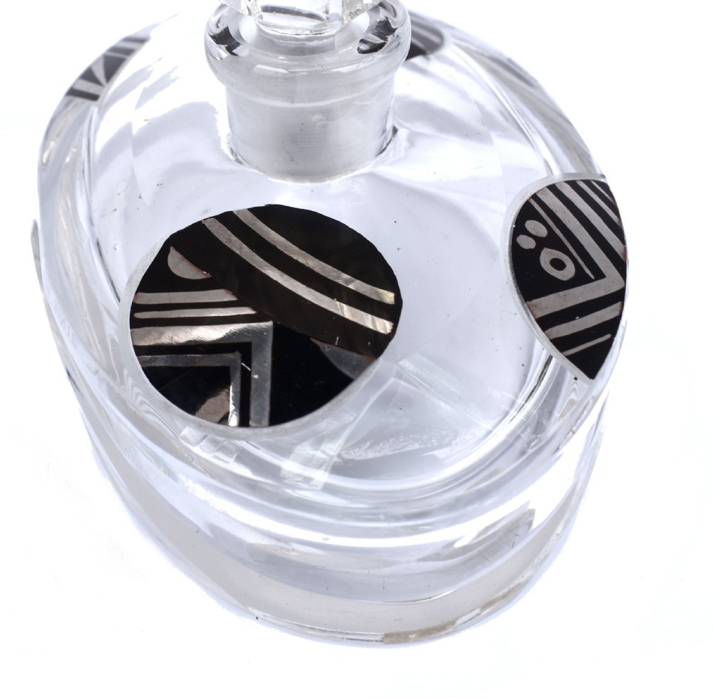 An Art Deco clear glass perfume bottle with angular cut facets, black enamelled fan details, and a matching tall stopper. View VII
