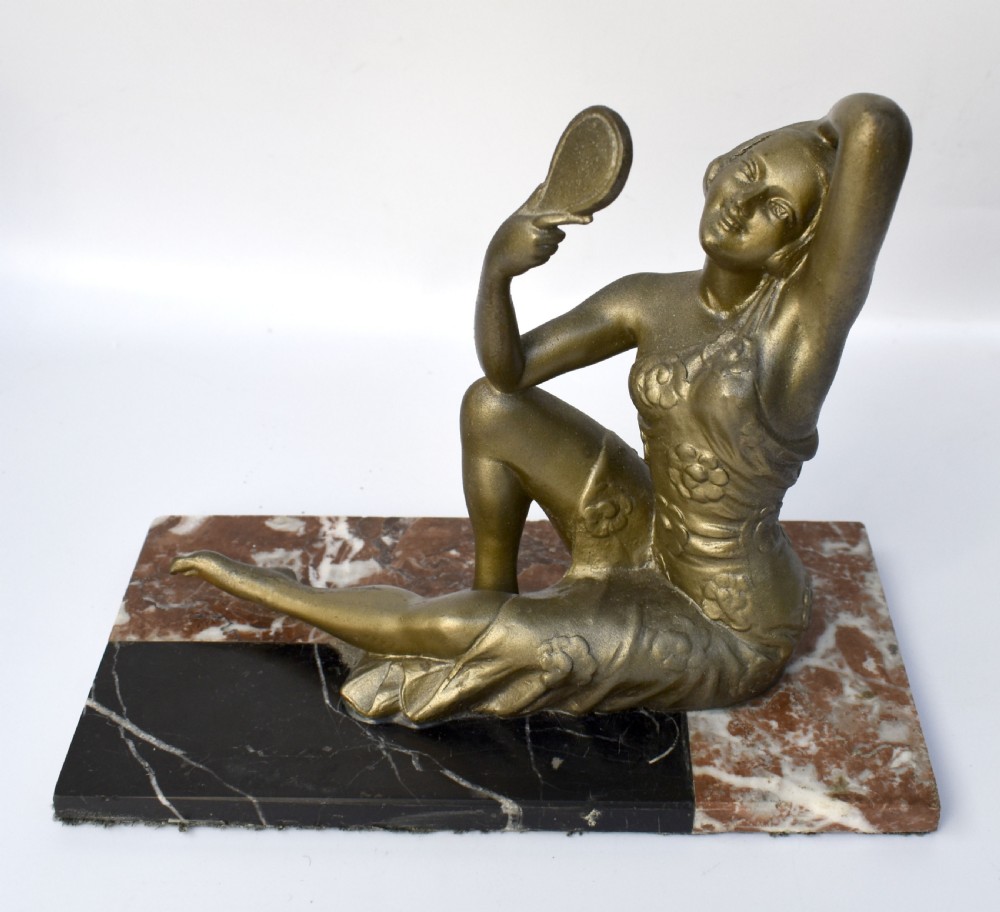 An Art Deco patinated metal figure of a seated woman holding a hand mirror, resting on a marble base. View V