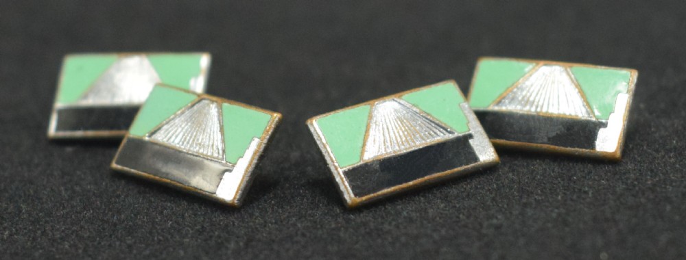 A pair of rectangular Art Deco cufflinks featuring green and black enamel with a central silver sunburst motif, connected by chain links. View IV