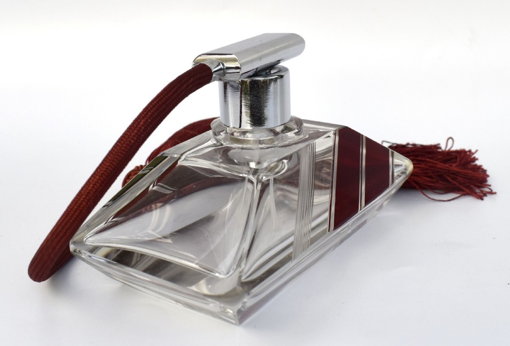 An Art Deco cut clear crystal glass perfume atomizer featuring a burgundy geometric inlay panel, chrome metal fitting, and a maroon fabric bulb with a fringe tassel. View V