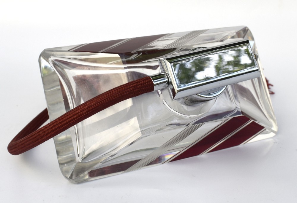 An Art Deco cut clear crystal glass perfume atomizer featuring a burgundy geometric inlay panel, chrome metal fitting, and a maroon fabric bulb with a fringe tassel. View VII
