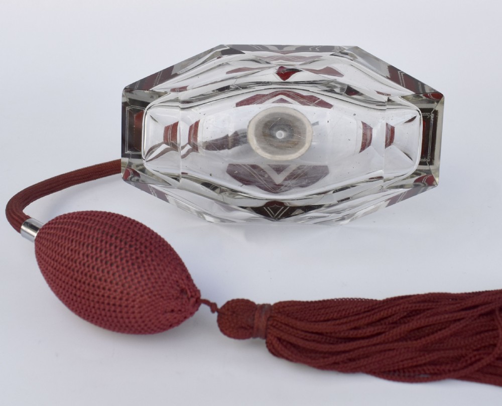 An Art Deco cut clear crystal glass perfume atomizer featuring a burgundy geometric inlay panel, chrome metal fitting, and a maroon fabric bulb with a fringe tassel. View IX