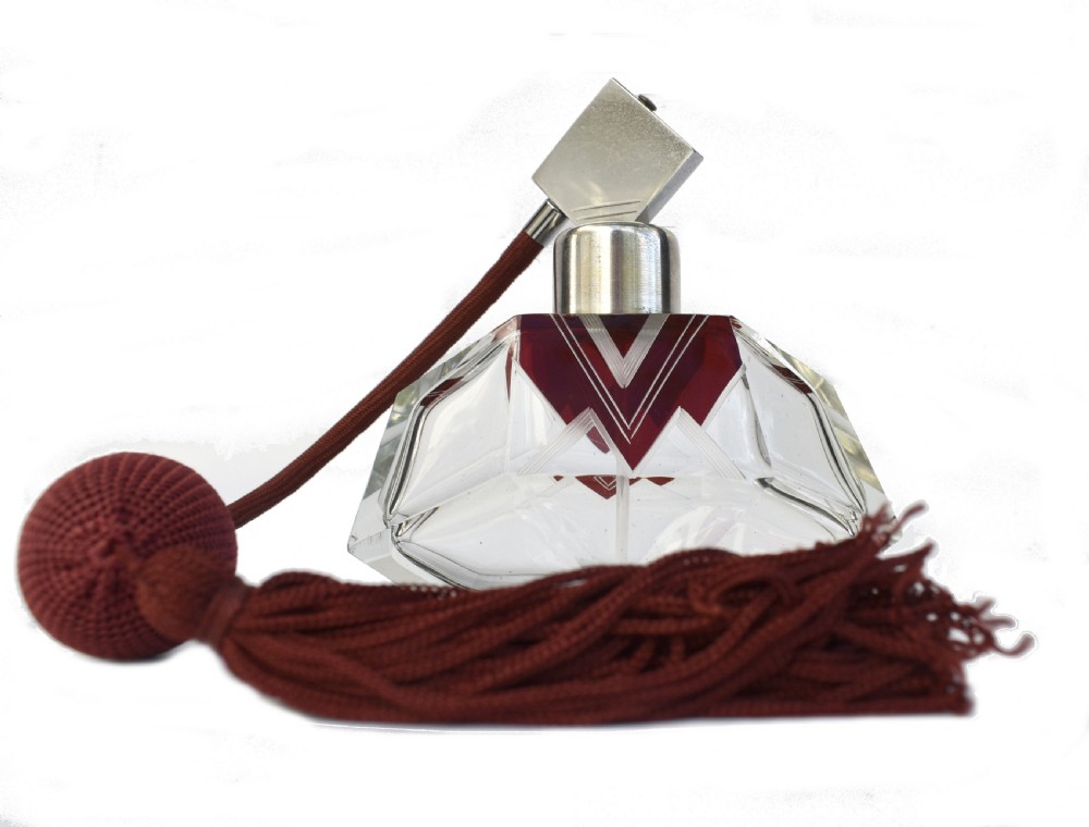 An Art Deco cut crystal perfume atomiser featuring burgundy geometric chevron detailing, chrome fittings, and a matching burgundy squeeze bulb with a long tassel.