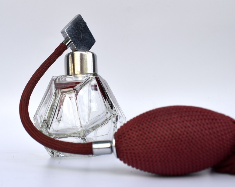 An Art Deco cut crystal perfume atomiser featuring burgundy geometric chevron detailing, chrome fittings, and a matching burgundy squeeze bulb with a long tassel. View II