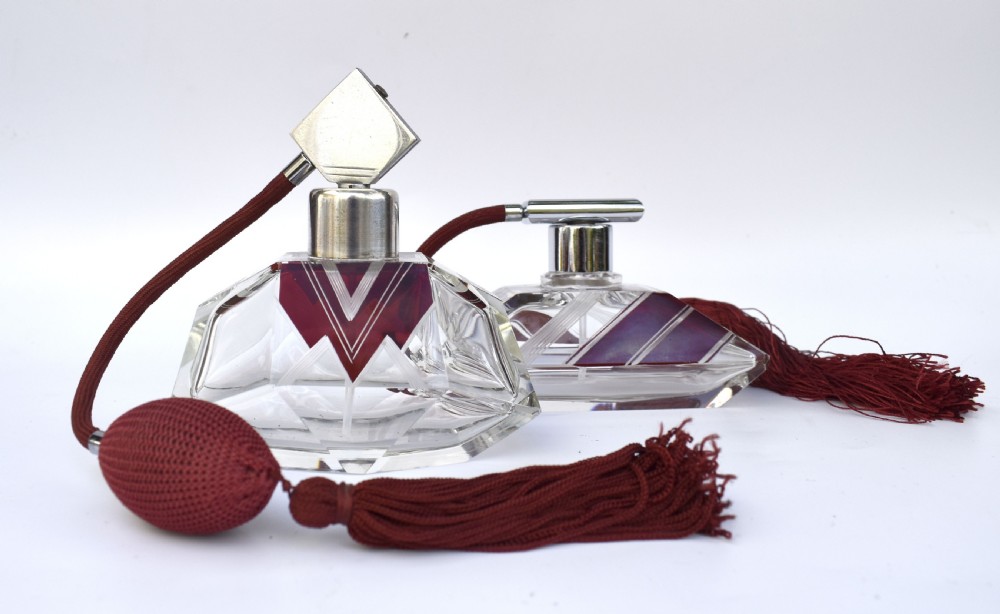 An Art Deco cut crystal perfume atomiser featuring burgundy geometric chevron detailing, chrome fittings, and a matching burgundy squeeze bulb with a long tassel. View VII