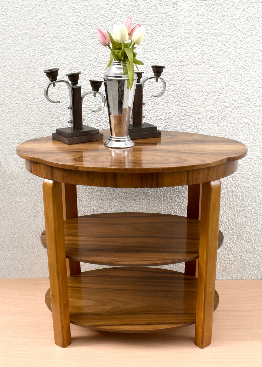 An Art Deco circular three-tier table made of figured walnut with smooth curved support legs. View X