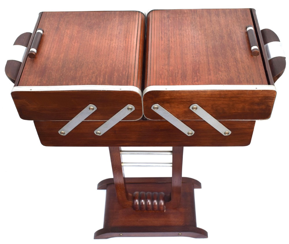 An Art Deco wooden cantilever sewing box on a pedestal stand with metallic joint brackets and cylindrical handles. View VI