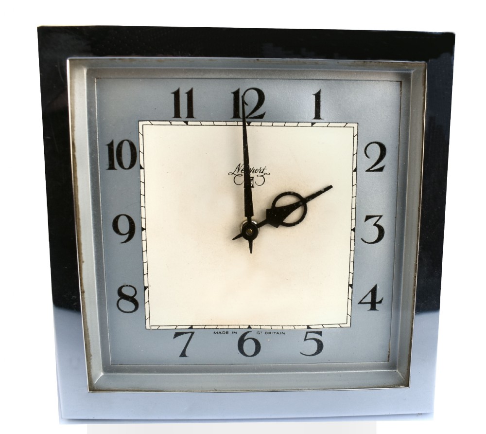 A square Art Deco chrome desk clock featuring a two-tone dial with black Arabic numerals and stylised hands.