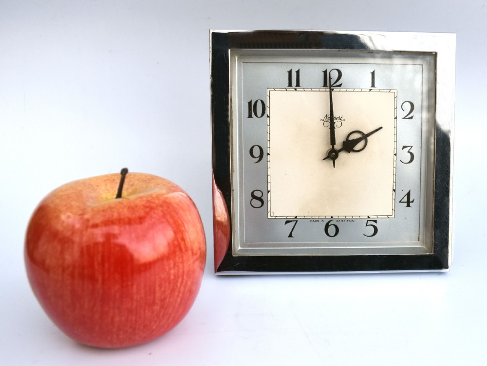 A square Art Deco chrome desk clock featuring a two-tone dial with black Arabic numerals and stylised hands. View III