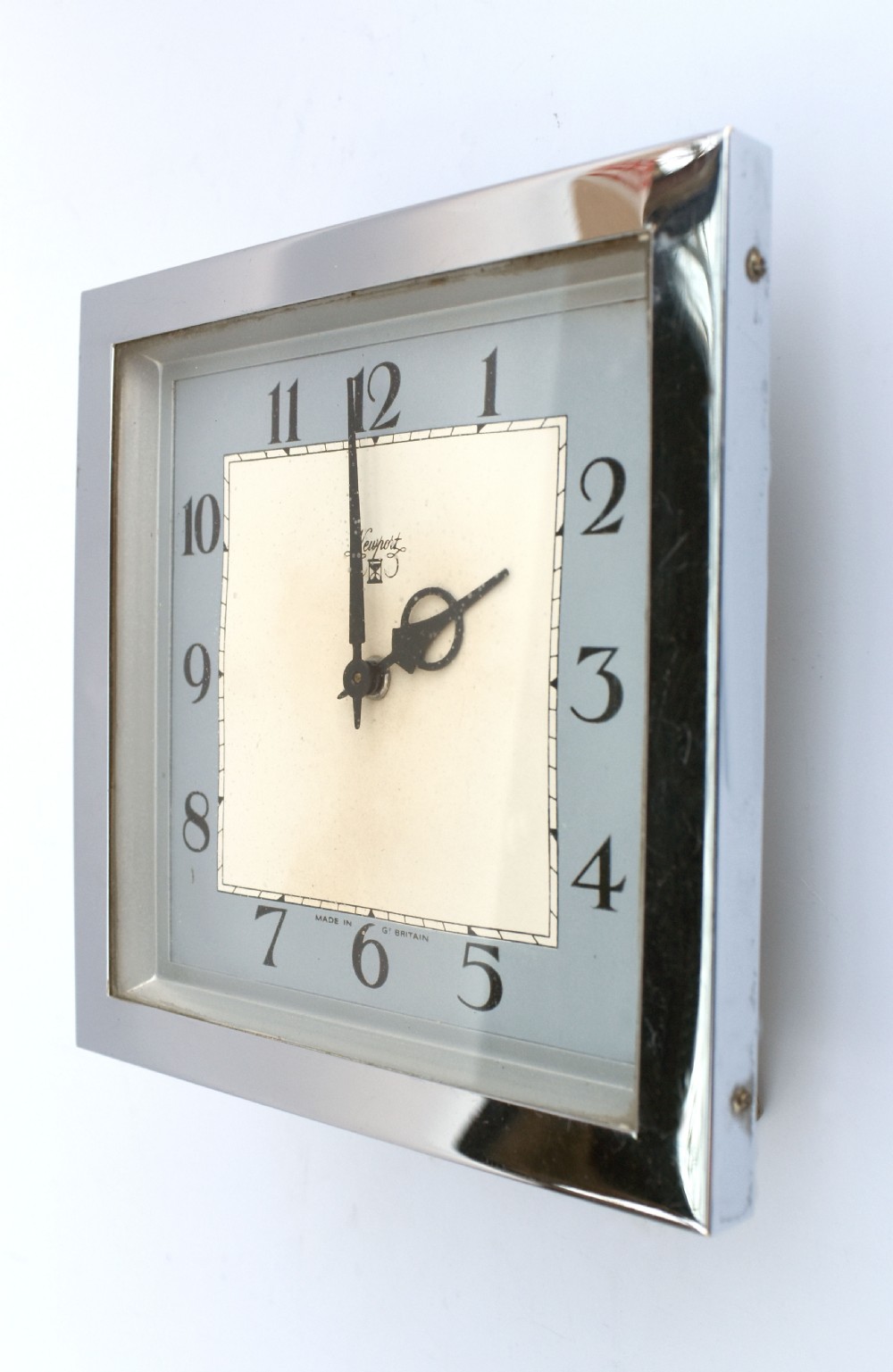 A square Art Deco chrome desk clock featuring a two-tone dial with black Arabic numerals and stylised hands. View V