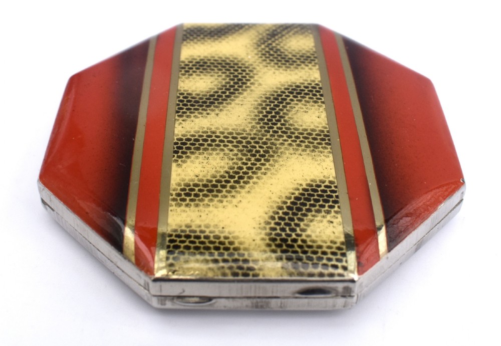 An octagonal Art Deco powder compact featuring terracotta red enamelled side panels and a central faux snakeskin section bordered by brass trim. View V