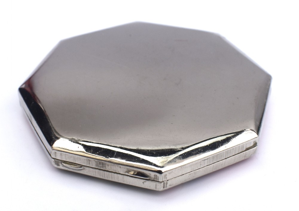 An octagonal Art Deco powder compact featuring terracotta red enamelled side panels and a central faux snakeskin section bordered by brass trim. View VII