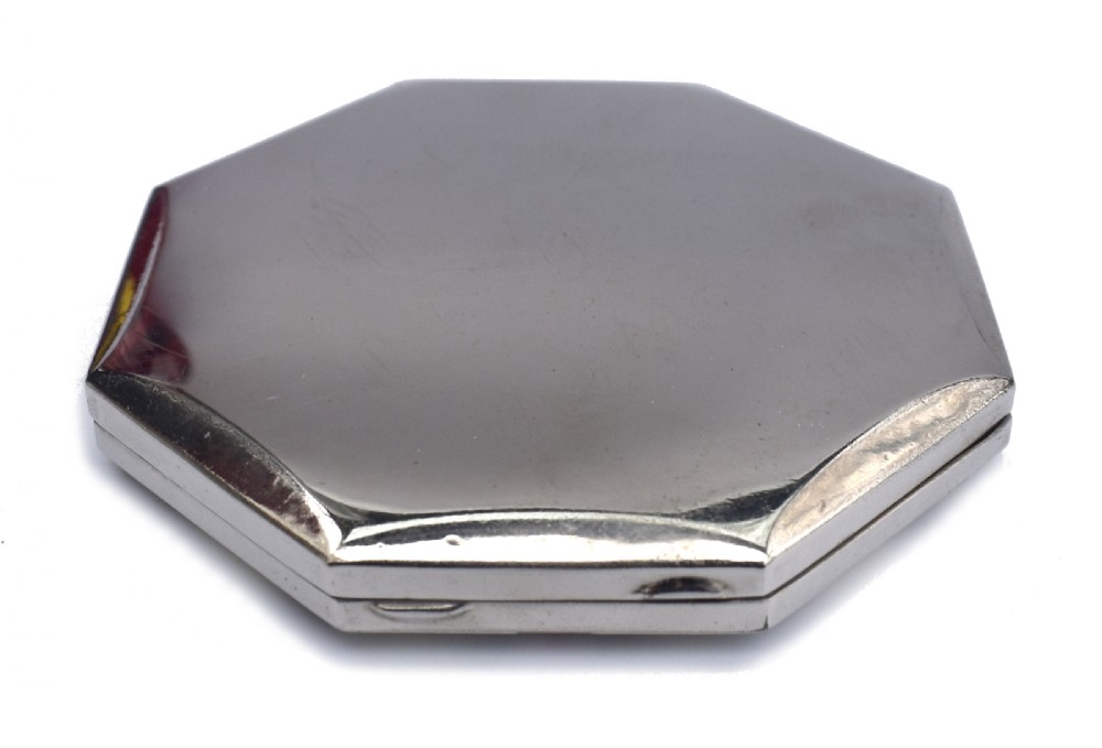 An octagonal Art Deco powder compact featuring a central red enamel chevron motif framed by a cream and black patterned ground. View VI