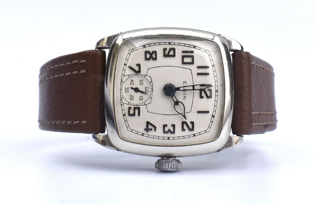 An Art Deco Elgin gentlemans wrist watch featuring a cushion-shaped 14k white gold case, cream dial with black Arabic numerals, small seconds dial, and a stitched brown leather strap. View V