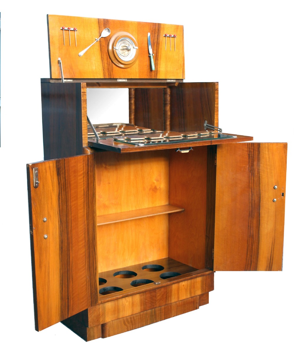 An Art Deco walnut cocktail cabinet featuring figure-matched timber grain, a drop-front upper section, double lower doors, and streamlined handles. View II