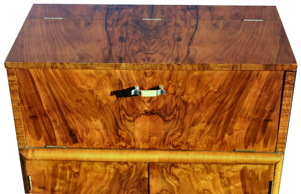 An Art Deco walnut cocktail cabinet featuring figure-matched timber grain, a drop-front upper section, double lower doors, and streamlined handles. View III