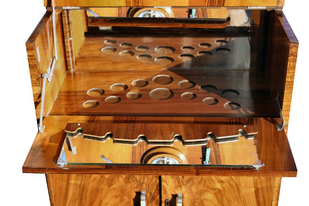 An Art Deco walnut cocktail cabinet featuring figure-matched timber grain, a drop-front upper section, double lower doors, and streamlined handles. View V