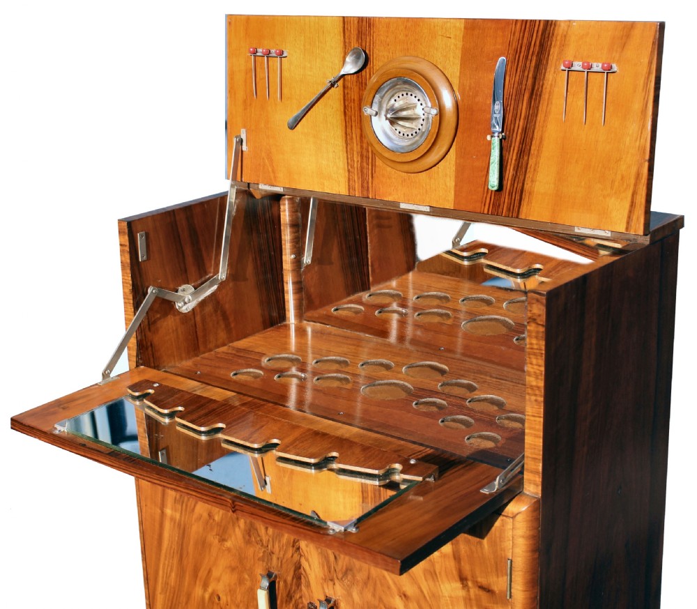 An Art Deco walnut cocktail cabinet featuring figure-matched timber grain, a drop-front upper section, double lower doors, and streamlined handles. View VI
