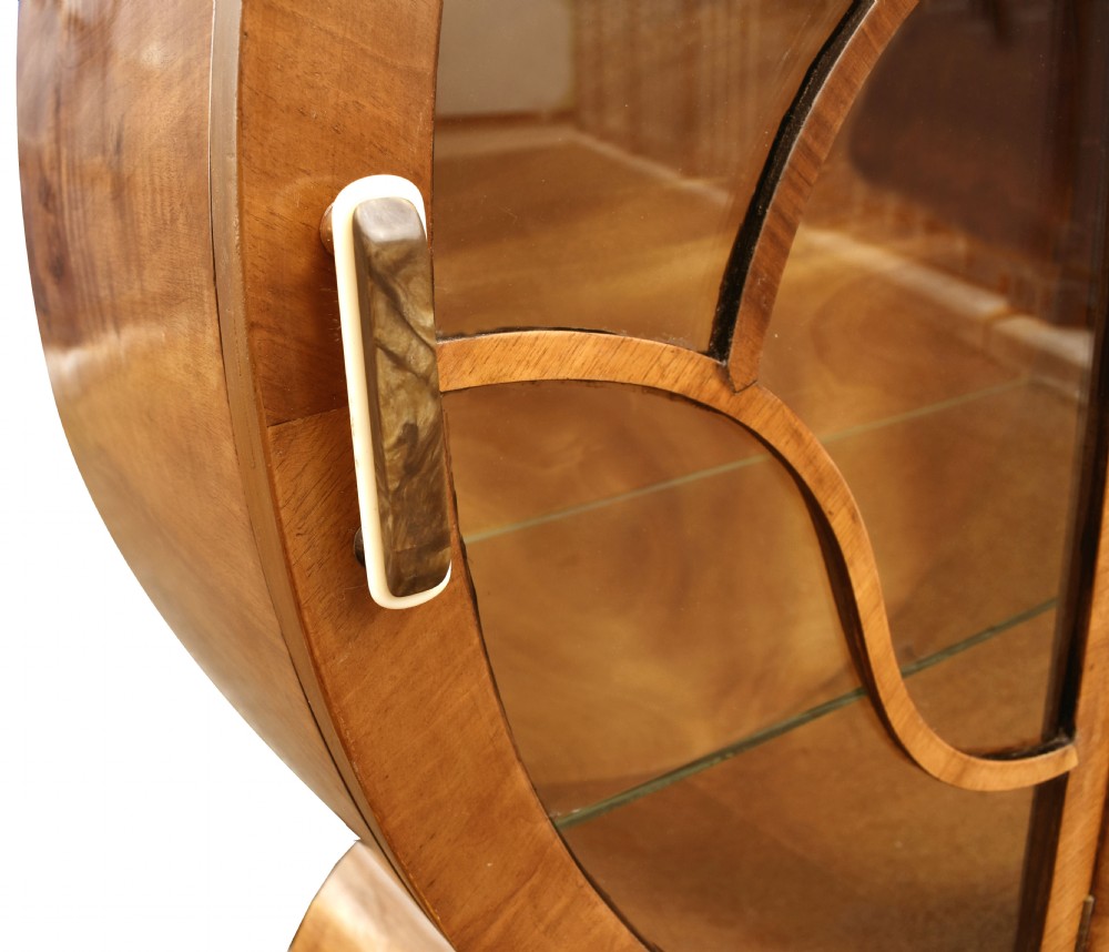 A circular Art Deco walnut display cabinet featuring glazed doors with geometric wooden glazing bars and a contoured base. View II