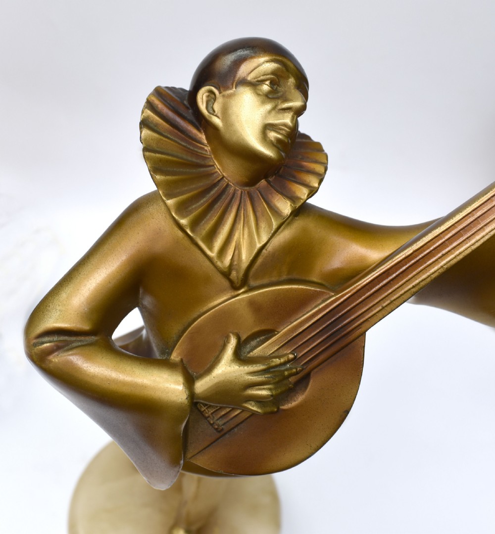 An Art Deco bronze figurine depicting a figure playing a mandolin, standing on a round cream onyx base. View III