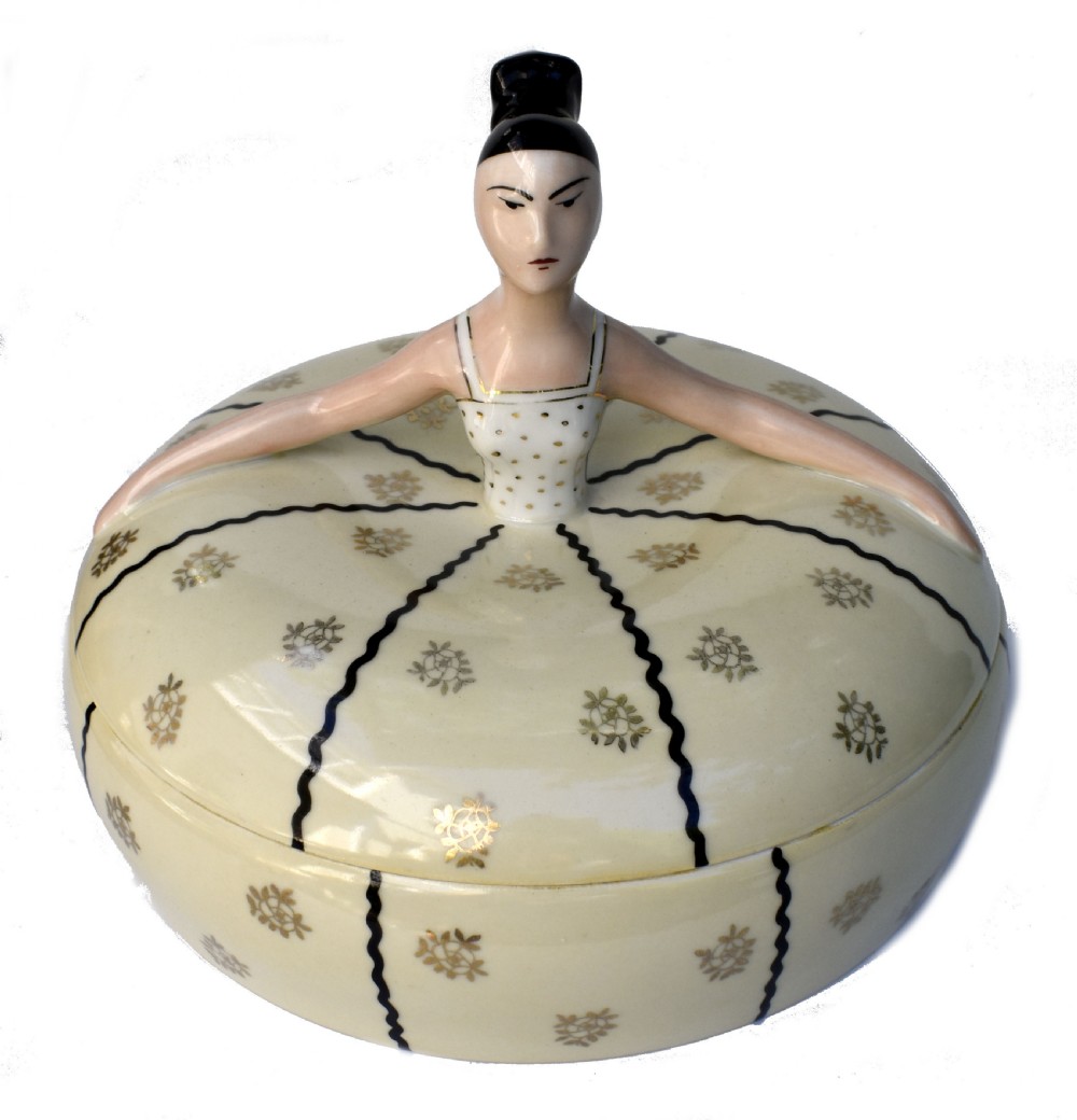 An Art Deco cream ceramic powder bowl with a lid sculpted in the form of a woman wearing a gown decorated with dark vertical wavy stripes and gilt floral motifs. View VI