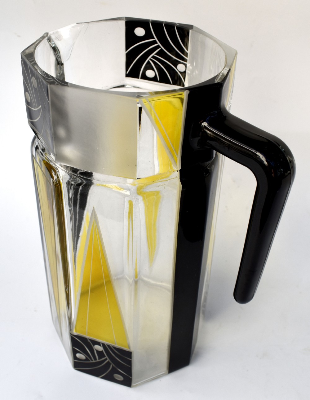 An Art Deco glass drinks set featuring a faceted glass pitcher and six matching tall glasses decorated with yellow and black geometric enamel patterns. View III