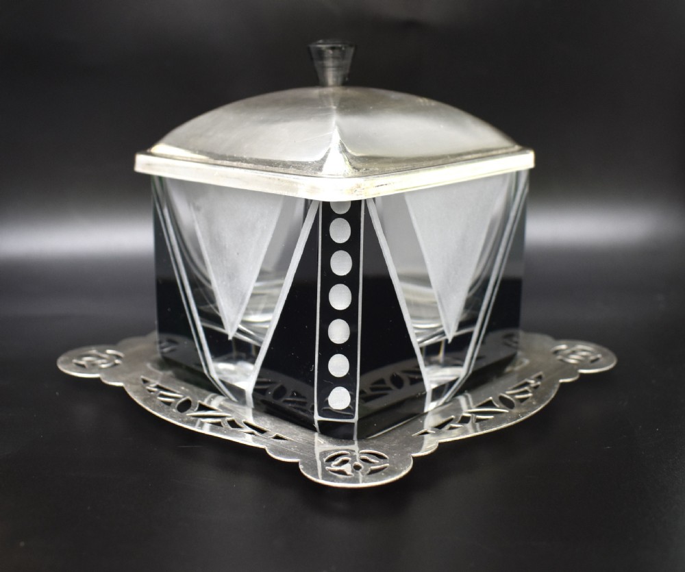 An Art Deco glass preserve dish featuring black and frosted geometric triangular motifs, topped with a silver-plated square lid and set on a pierced silver-plated tray. View III
