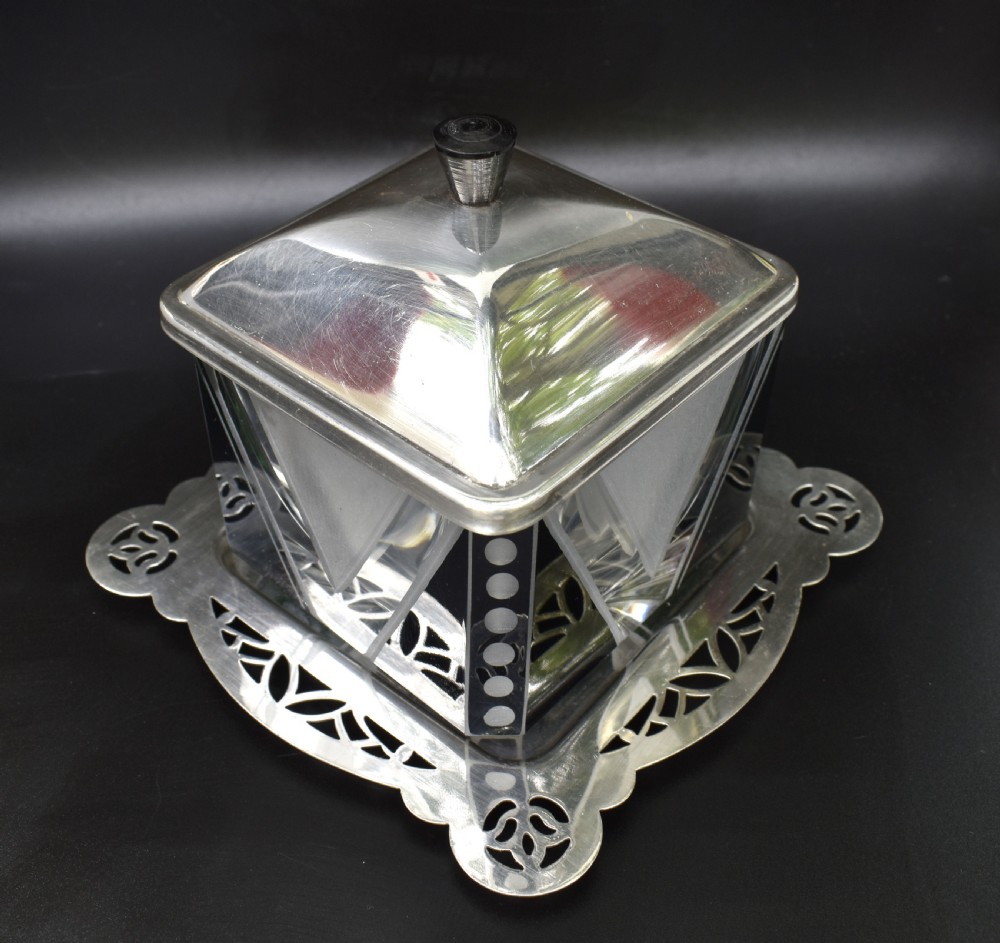 An Art Deco glass preserve dish featuring black and frosted geometric triangular motifs, topped with a silver-plated square lid and set on a pierced silver-plated tray. View IV