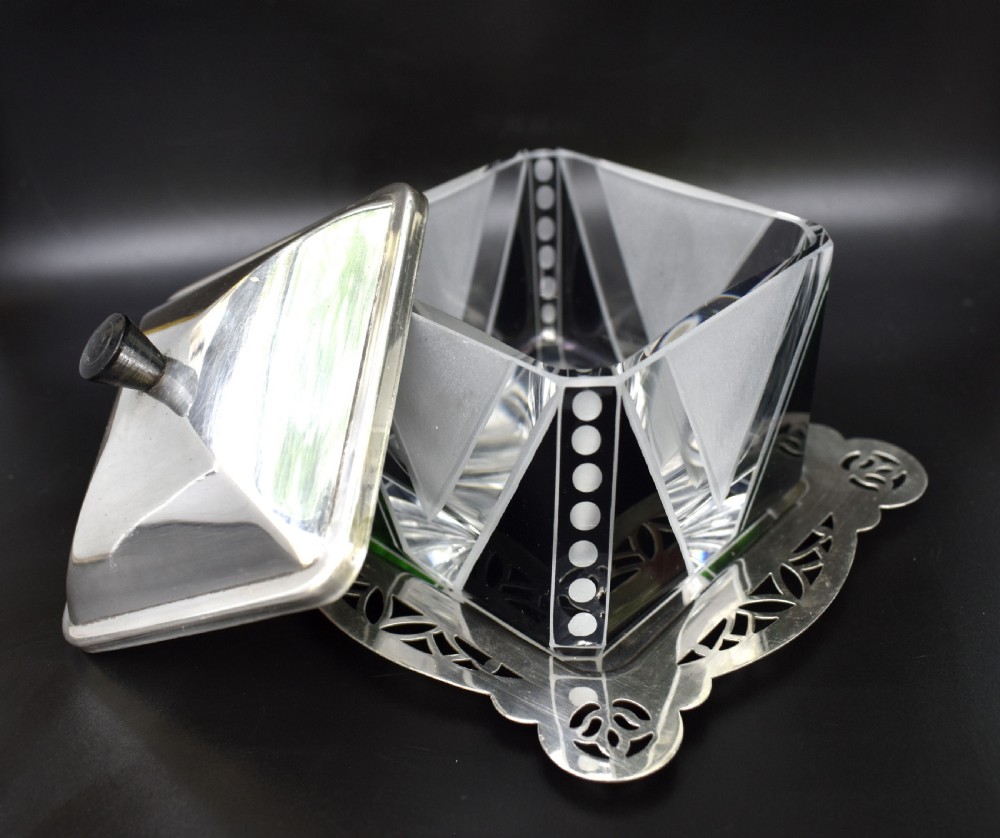 An Art Deco glass preserve dish featuring black and frosted geometric triangular motifs, topped with a silver-plated square lid and set on a pierced silver-plated tray. View V