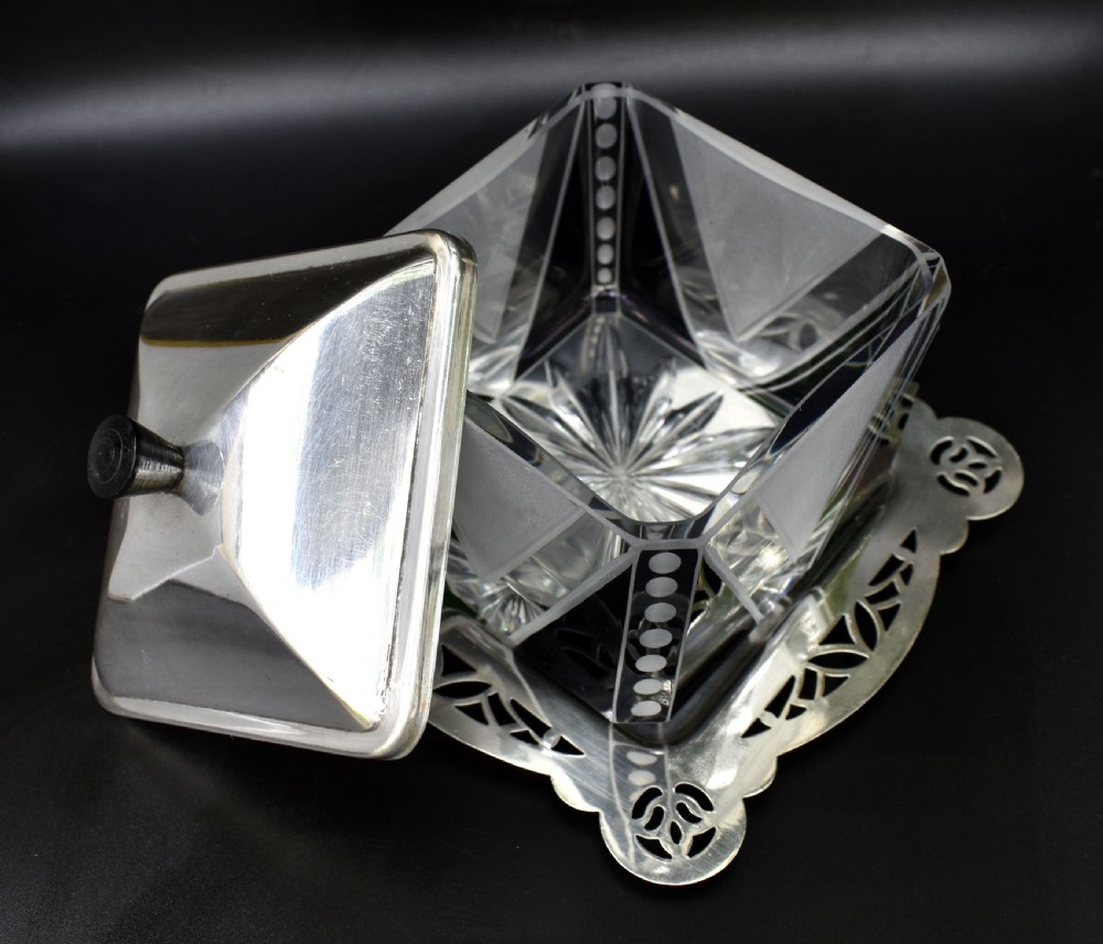 An Art Deco glass preserve dish featuring black and frosted geometric triangular motifs, topped with a silver-plated square lid and set on a pierced silver-plated tray. View VI