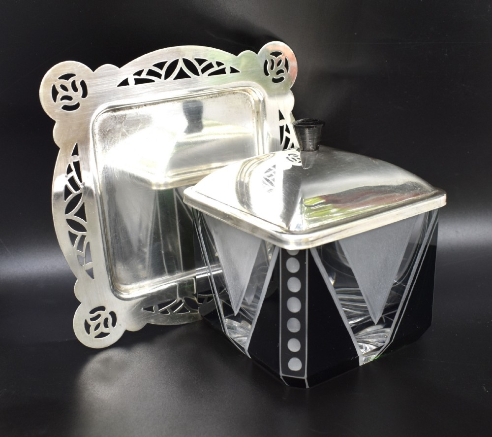 An Art Deco glass preserve dish featuring black and frosted geometric triangular motifs, topped with a silver-plated square lid and set on a pierced silver-plated tray. View VII