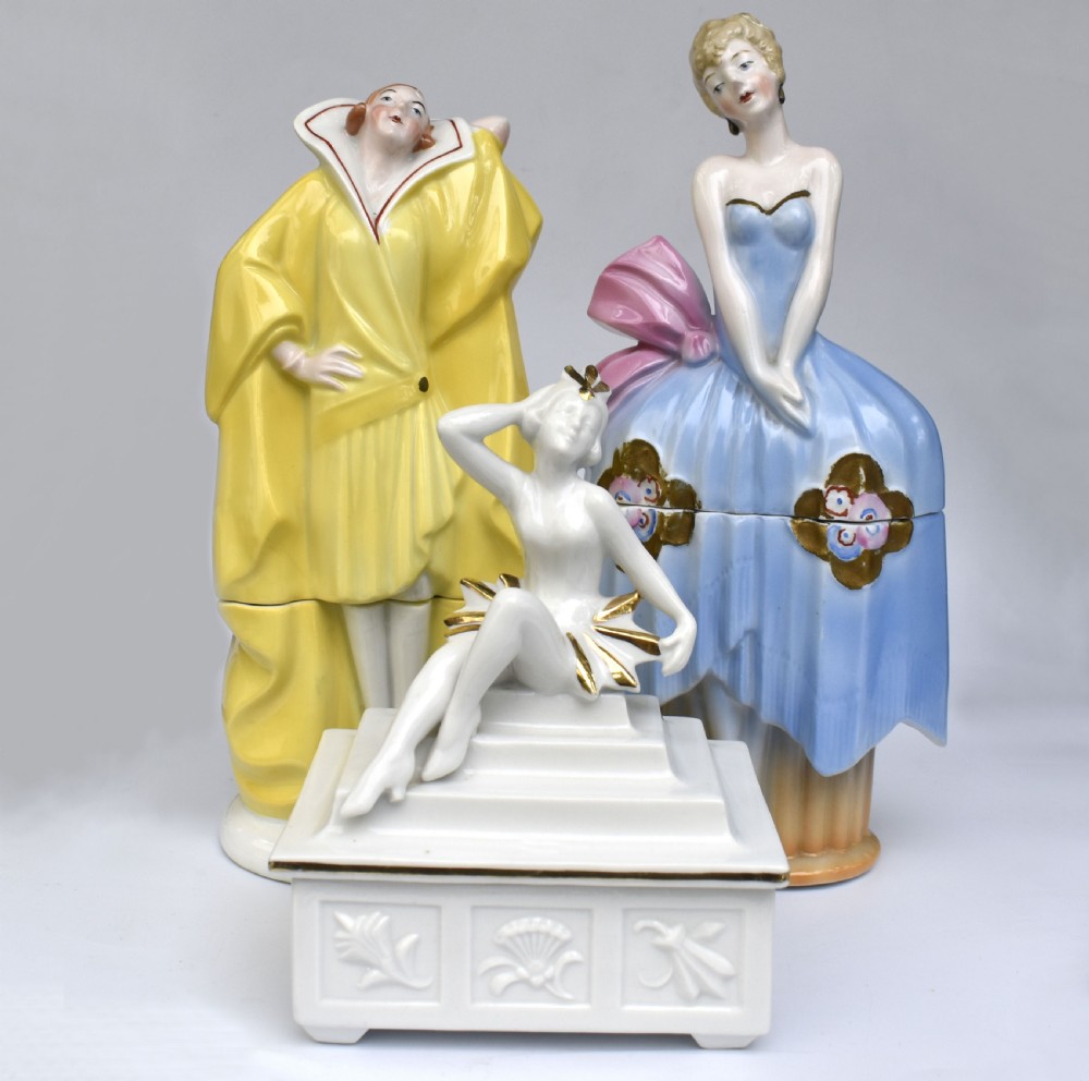 A white glazed porcelain Art Deco powder box featuring a lid topped with a seated female figure accented with gold gilding. View VI