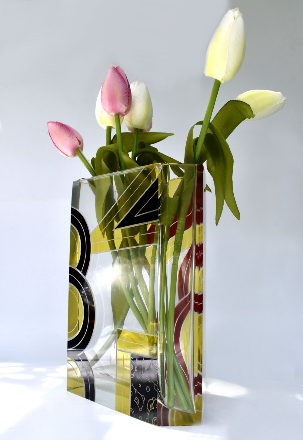 A rectangular clear glass Art Deco vase decorated with etched patterns and enamelled geometric shapes in black, yellow, and red. View III